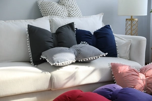 Detailed view of striped bow-shaped pillow featuring white pom-pom edges for home decor