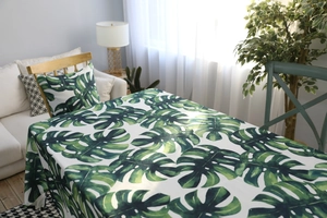 Détail de la nappe imperméable à motif monstera et du coussin assorti dans le salon