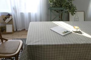 Detailed close-up of grey plaid linen tablecloth with elegant drape on a wooden dining table