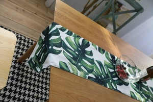 Close-up of Monstera leaf print table runner on a wooden dining table in Nordic style