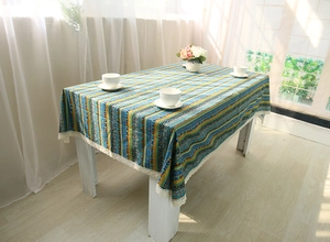 Detail of bohemian colorful striped tablecloth with decorative white lace edges on table