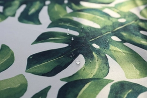 Gros plan détaillé de gouttes d'eau sur une nappe imperméable aux motifs de monstera