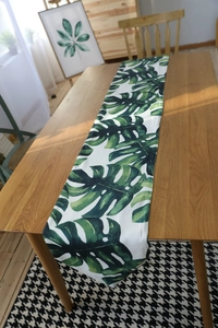 Detailed close-up of a Nordic table runner with vibrant green Monstera leaf prints