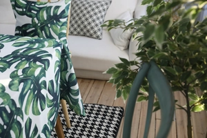 Détail d'une nappe en coton imperméable aux feuilles de Monstera et housses de chaise