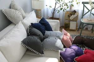 Detail of cute striped bow pillow with white pom-poms on the edges for home decor