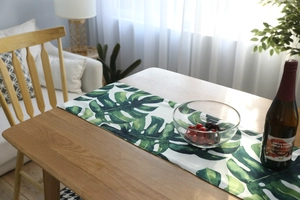 Detailed close-up of tropical Monstera leaf pattern on breathable linen table runner