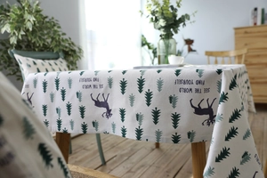 Detail of linen tablecloth featuring green pine trees and reindeer pattern for home decor