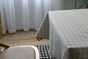 Detail of grey checked cotton linen tablecloth with elegant drape in a bright room