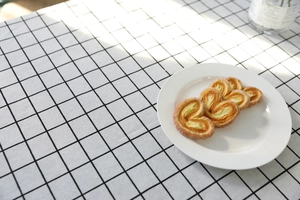 Vista macro di quattro palmiers croccanti su piatto bianco e tovaglia a quadretti