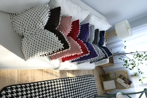 Detail of colorful bow-shaped throw pillows with pom-poms on a white sofa in a cozy room