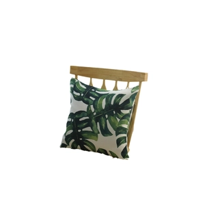 Square cushion with tropical green monstera leaf print on a white wood chair