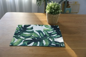 Vue détaillée des coutures fines et du motif de feuilles de Monstera de la nappe verte