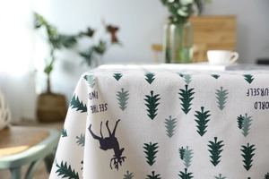 Close-up of linen fabric with green forest trees and elk prints on a dining table