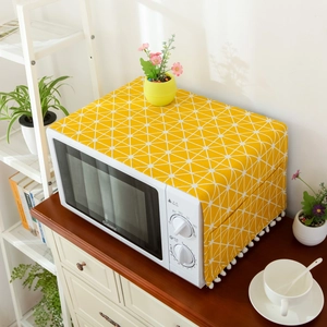 Detail of yellow geometric microwave dust cover with white tassels and side storage pockets