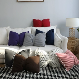 Detail of bow-shaped pillows with white pom-pom edges and striped fabric textures