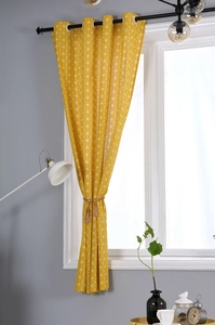 Detail of yellow cotton linen curtain with white geometric patterns and tassel tieback