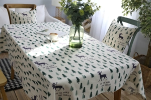 Detail of linen tablecloth with purple deer and green pines in a cozy setting