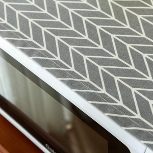 Gray and white geometric arrow linen microwave dust cover on a white kitchen appliance