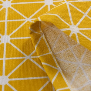 Detail of yellow geometric pattern on linen cotton curtains showing stitching and texture