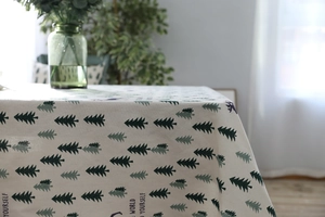Detail of linen tablecloth featuring green pine trees and elk silhouettes in Nordic style