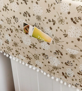 Detail of grey linen cover with white hydrangea print and plush ball tassel decoration