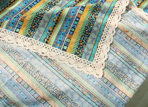 Close-up of bohemian linen tablecloth featuring colorful geometric patterns and lace trim