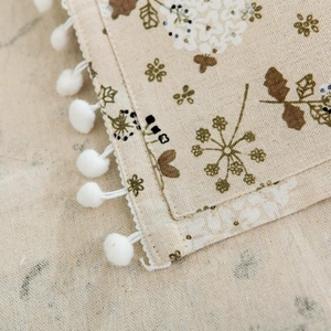 Close-up of gray hyacinth linen washing machine cover with elegant white pom-poms edge