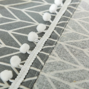 Detail of grey cotton linen microwave cover with white branches and pom-pom fringe