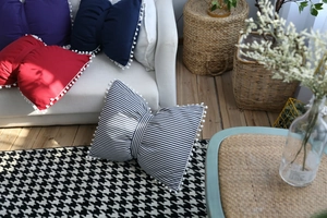 Detailed view of colorful bow-shaped cushions with cute pom-pom trim in a cozy setting