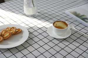 Dettaglio della tovaglia a quadretti neri e bianchi sotto caffè e dolci squisiti