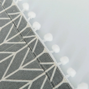 Macro detail of Nordic grey linen microwave cover with white chevron pattern and pom-poms
