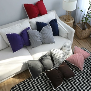 Nordic bow-shaped throw pillows with pom-pom trim in solid and striped patterns