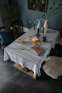 Close-up of white crochet tablecloth featuring intricate floral patterns and scalloped edges