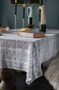 Detail of white crochet tablecloth featuring intricate geometric floral patterns and lace edges