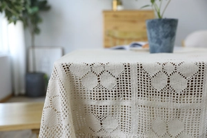 Detailed macro view of beige handmade crochet lace tablecloth with floral hollow patterns