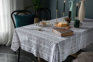 Detail of white lace crochet tablecloth with intricate floral hollow out pattern for dining table
