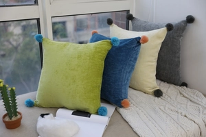 Close-up of soft velvet pillowcases with striped texture and colorful corner pom-poms