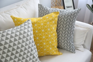 Dettaglio delle federe per cuscini geometrici in cotone e lino giallo e grigio