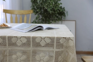 Close-up of vintage hand-crocheted beige lace tablecloth with hollow geometric floral patterns