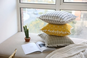 Detail of Nordic cotton linen pillowcases with geometric patterns and white pom-poms