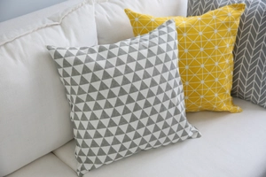 Dettaglio delle trame geometriche dei copricuscini decorativi nordici grigi e gialli