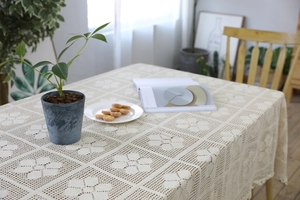 Detail of cream white crochet tablecloth featuring large floral patterns and lace edges