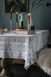 Detailed close-up of white crochet lace tablecloth with hollow patterns and wavy edges