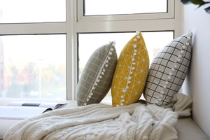Detailed view of cotton linen lumbar pillows with white pom-poms and geometric patterns