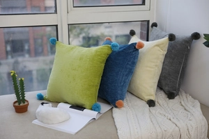 Detailed texture of velvet square pillows with contrast pom-poms in Nordic home setting