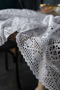 Close-up of white crochet lace table runner with hollow floral pattern and scalloped edges