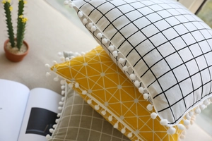 Detail of Nordic cotton linen pillow covers with geometric patterns and white pom-poms