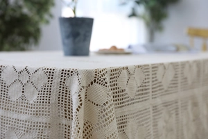 Detailed close-up of ivory handmade crochet lace tablecloth with vintage floral patterns