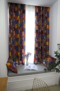 Dettaglio di tende boho con stampa paisley e cuscini coordinati con motivi etnici