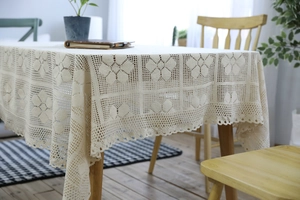 Close-up detail of vintage hand-crocheted lace tablecloth with floral hollowed pattern
